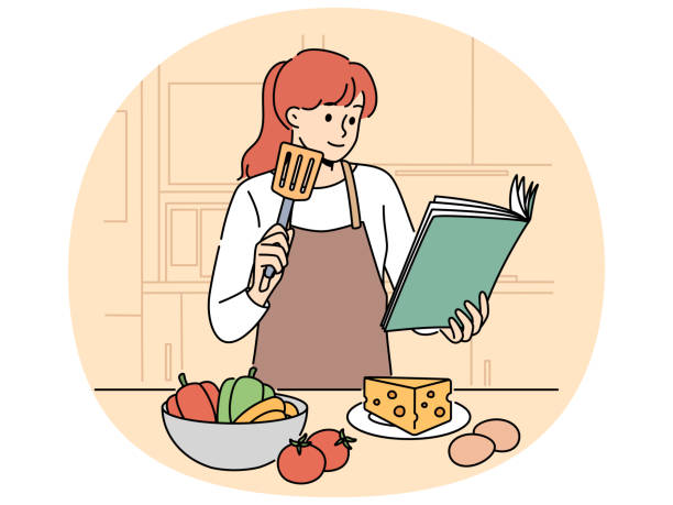 料理の具材の前で料理本を見ている女性
