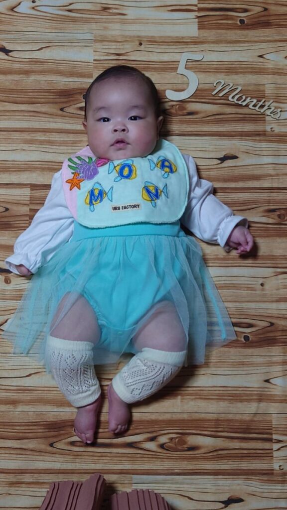 床に横たわるよだれかけを着ている赤ちゃん
