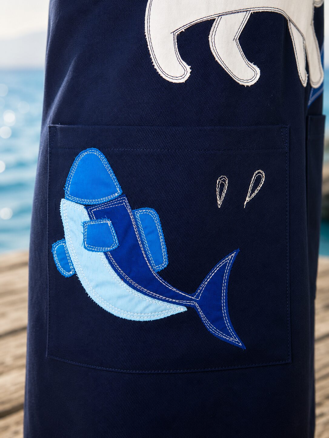 エプロンに縫われた魚のアップリケの拡大画像